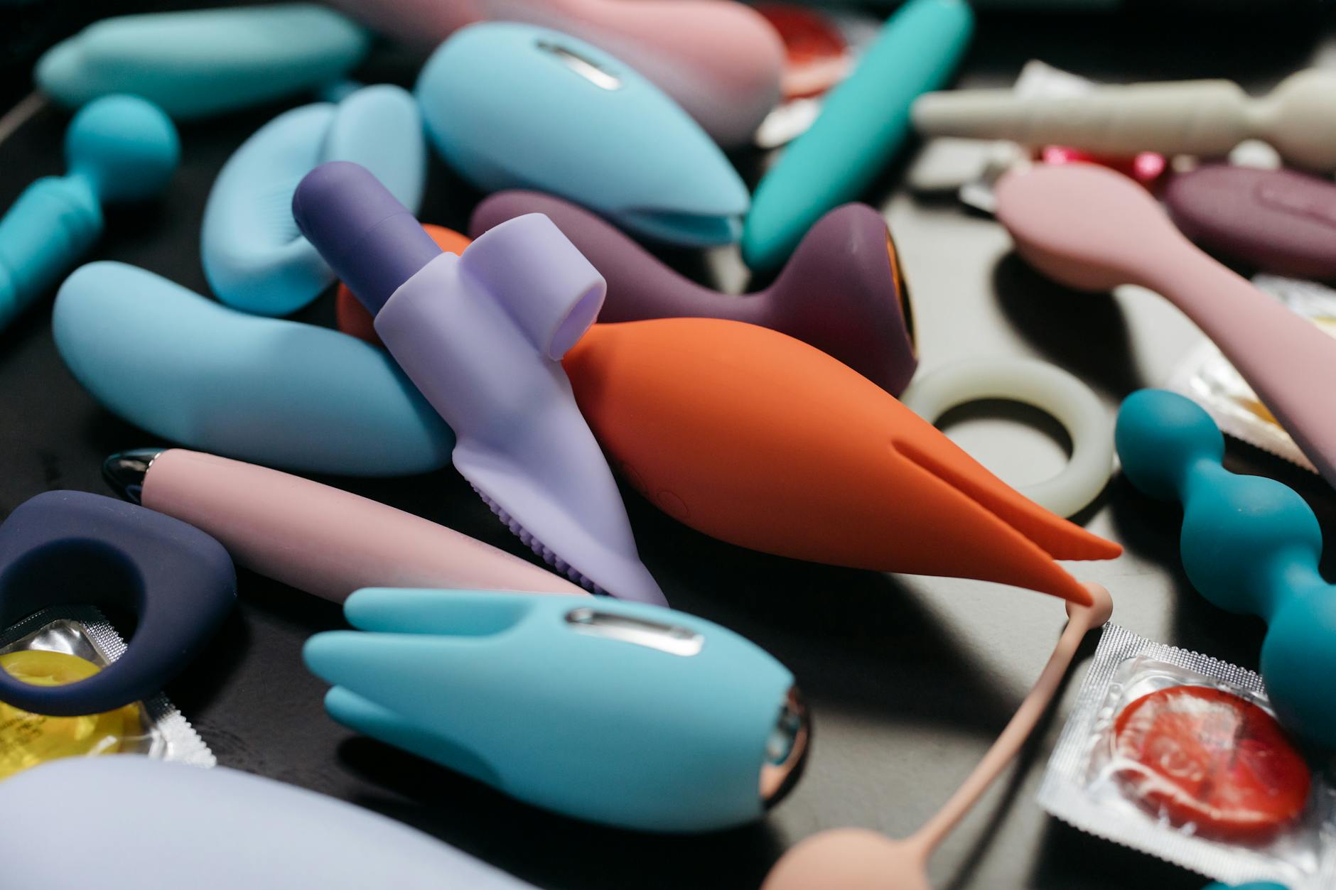 Woman holding a pink vibrator with art books nearby, representing solo pleasure and intimacy