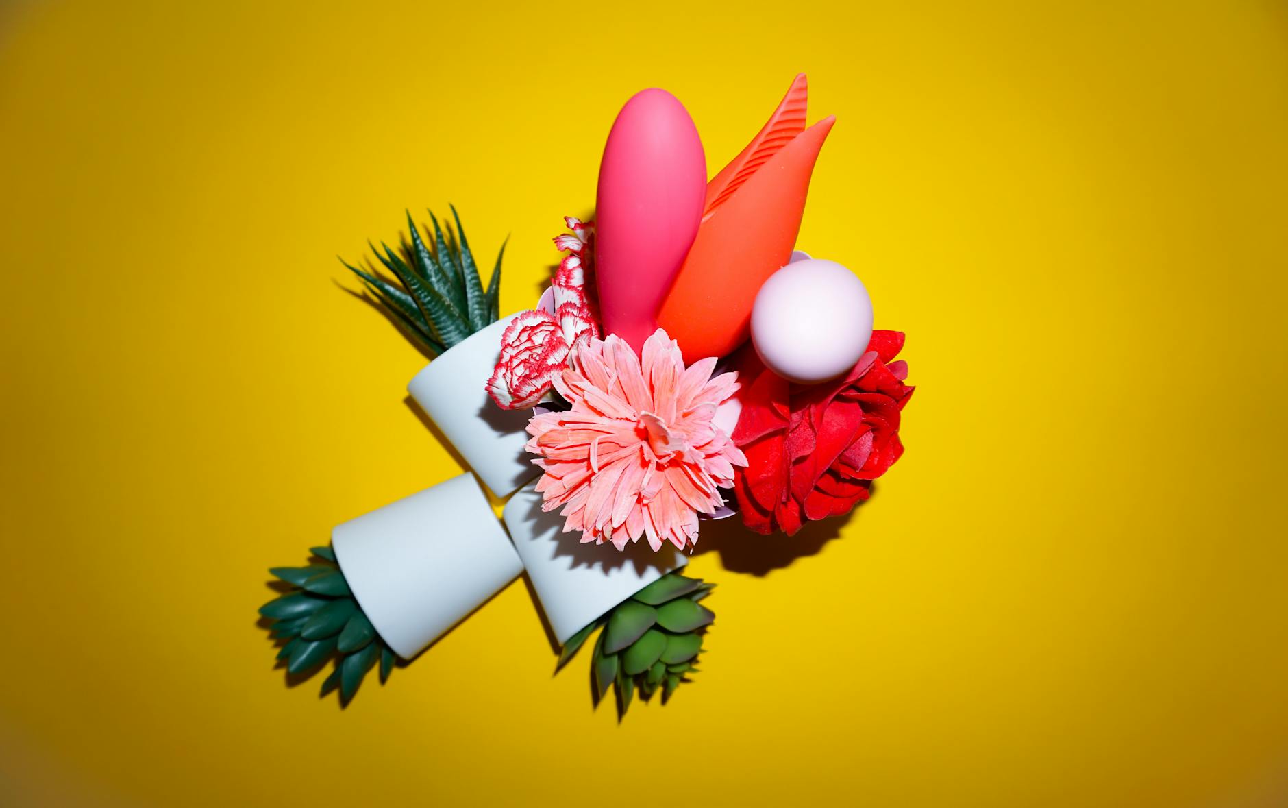A hand holding an orange vibrator against a minimalistic purple backdrop